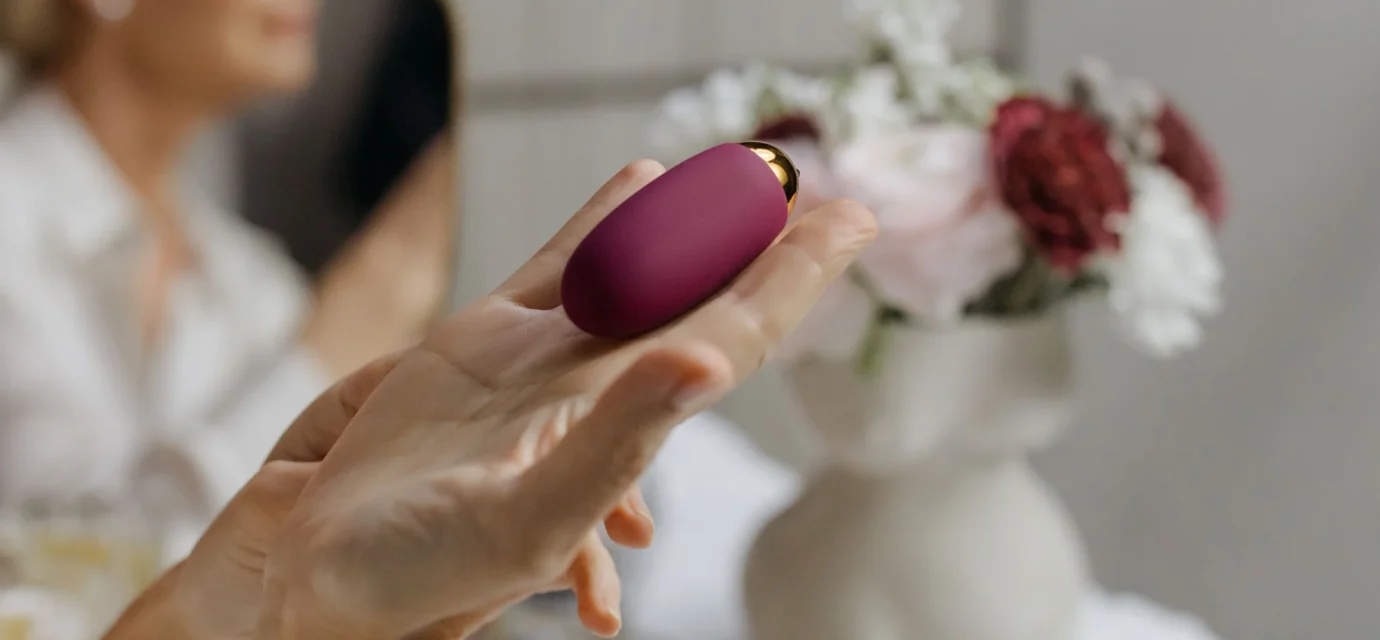 A hand holding a compact purple personal massager