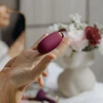 A hand holding a compact purple personal massager