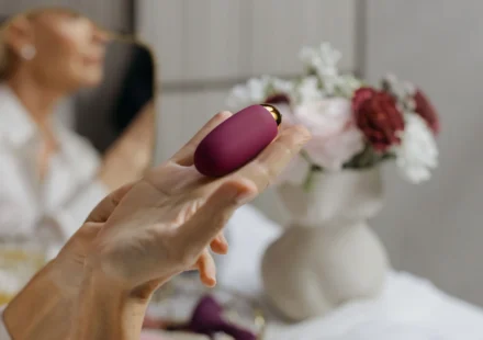 A hand holding a compact purple personal massager