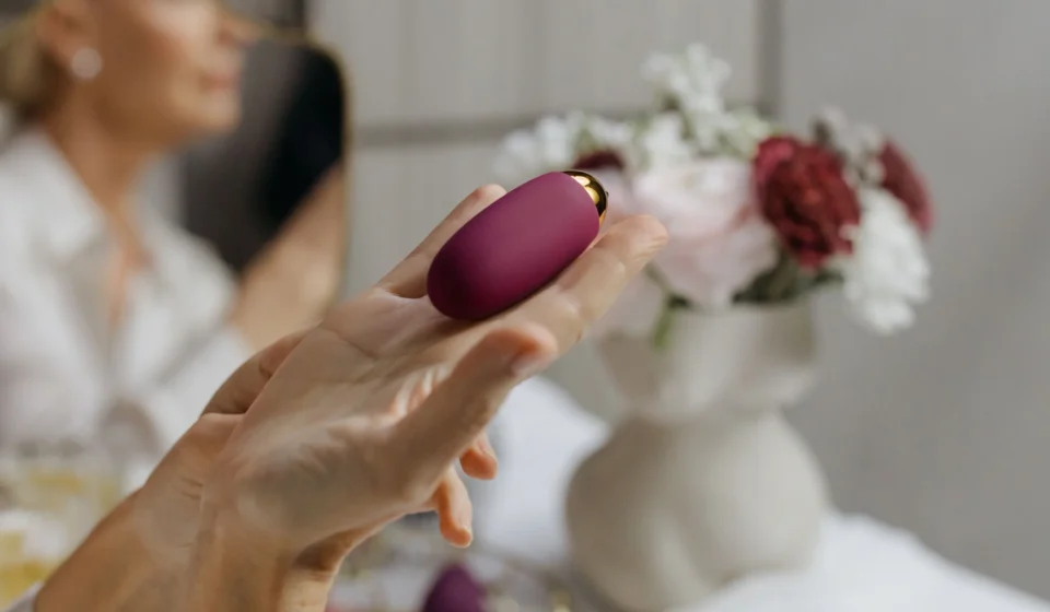 A hand holding a compact purple personal massager