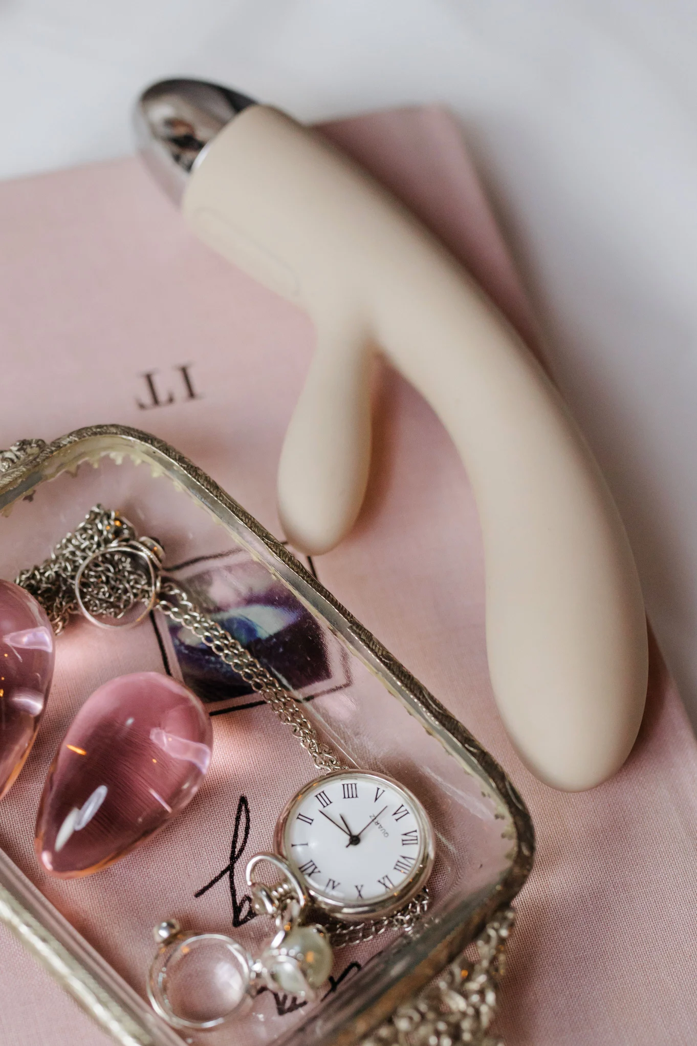 A white curved personal massager beside jewelry