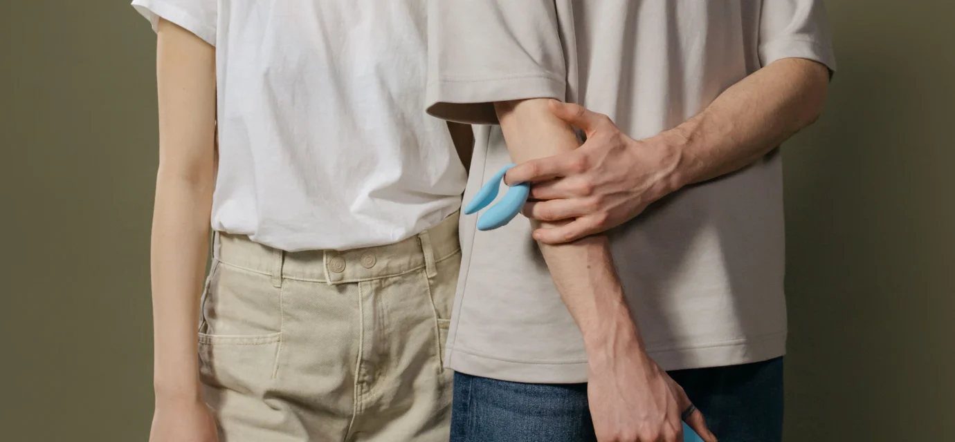 Two adults standing together while one person holds a blue intimate product