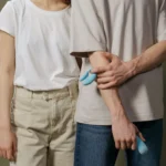Two adults standing together while one person holds a blue intimate product
