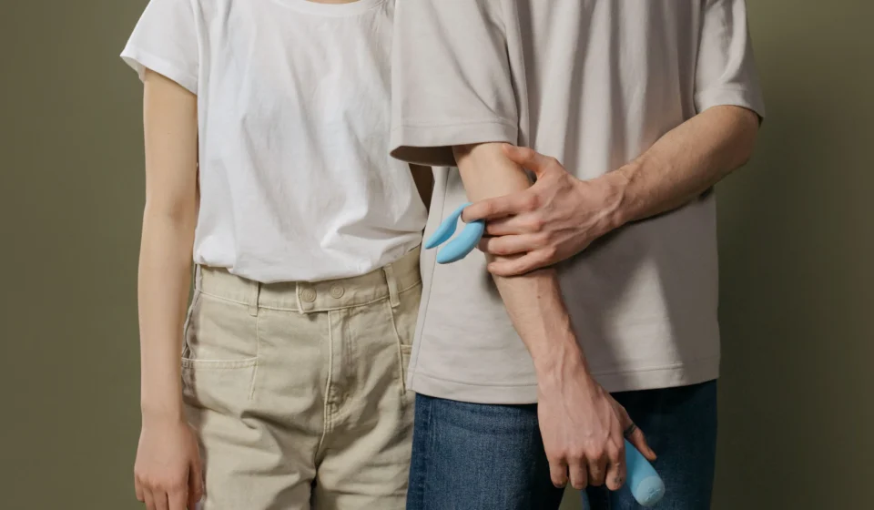 Two adults standing together while one person holds a blue intimate product