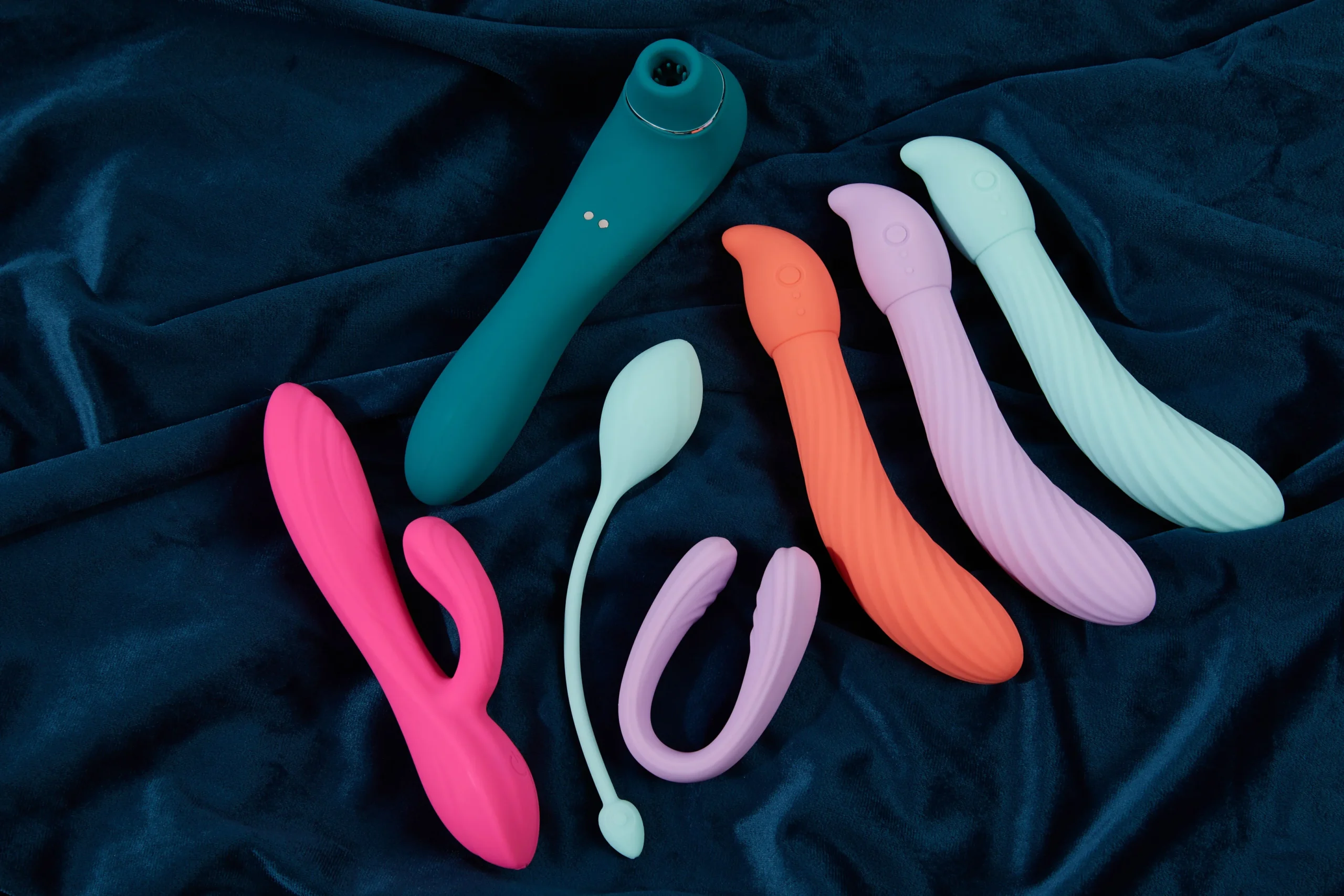 A selection of colorful sex toys arranged on dark fabric